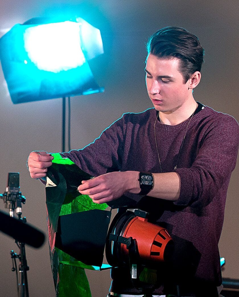 Student adjusting the lighting on set